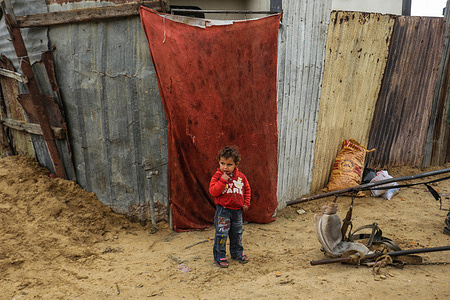 A Palestinian refugee child plays outside his family's home during cold weather in a slum in the northern Gaza Strip.With high rates of unemployment in Gaza, an increasing number of families are facing poverty after losing their jobs during the last ten years of Gaza siege and three Israeli wars against Gaza Strip.