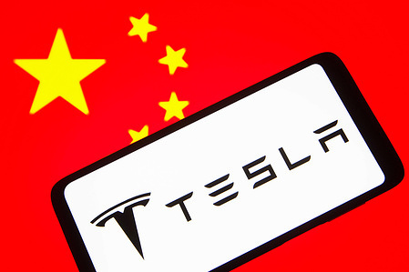 In this photo illustration, the Tesla, Inc. logo is seen on a smartphone screen and flag of China in the background.