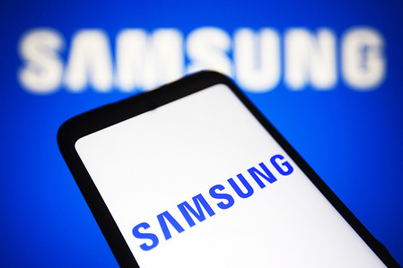 In this photo illustration, Samsung Group logo seen displayed on a smartphone and a computer screen.