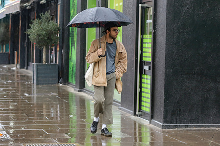 A man shelters under his umbrella during a rainfall.
According to the Met Office, milder weather with 10 degrees Celsius is forecasted up to next week.