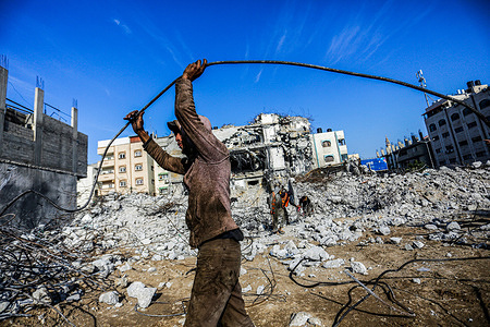 A Palestinian worker collects scrap metal while removing the debris of the Al-Jawharah Tower that was hit by the Israeli airstrikes during Israel-Palestine war in May 2021.