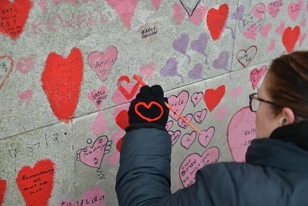 Volunteer paints new hearts on The National Covid Memorial Wall, just outside St Thomas' Hospital, in London.