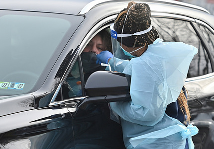 A health worker wearing a Personal Protective Equipment (PPE) gear collects a nasal swab sample froma woman at a drive-thru testing site.
With the surge of the new Covid-19Omicron variant, testing sites are seeing long lines of people wanting to avail the testing. Employees from AMI Expeditionary Healthcare are seen in Pennsylvania giving Covid-19 tests. The group has been moving from one hotel to another and working 12 hours a day and 4 to 5 days a week to facilitate the covid-19 testing of the public.