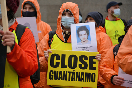 A protester holds a placard that says Close Guantanamo and portrait of detainee during the demonstration. 
Amnesty International activists dressed in orange jumpsuits and hoods, representing the 39 men still held in the Guantanamo Bay detention camp, marched from Parliament Square to Trafalgar Square marking 20 years of the Camp. They were calling for inmates to either charged or released and for the camp to be closed.