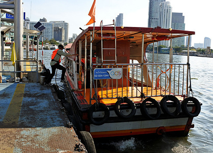 An express boat rope handler jumps onto an express boat at a pier.
Bangkok’s Chao Phraya River Express Boat passenger service from Bangkok to Nonthaburi. Established in 1971 the waterway transportation system using motorized passenger boats ferry people along the river, a popular mode of transport for locals and tourists.