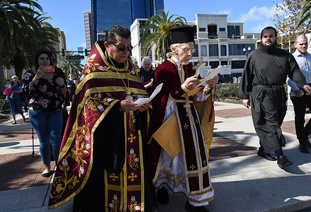 Fr. John Hamatie (center right) and other clergy members walk to the Lake Eola for the annual Epiphany cross dive celebration held at the St. George Orthodox Church in downtown Orlando. 
The celebration honors the baptism of Jesus Christ and it is said that the person who retrieves the cross will receive good luck for the rest of the year.