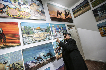 A Palestinian painter Muhammad al-Astal, 84 years old, points one of his paintings displayed in his house in the Southern Gaza Strip which he turned into a permanent art exhibit of his paintings for more than 60 years embodying reality, Palestinian lifestyle, and Arab heritage.
