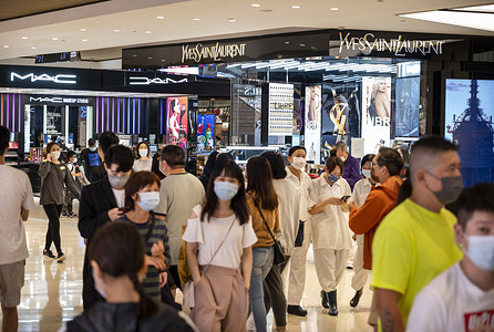 Shoppers walk past the French luxury fashion brand Yves Saint Laurent (YSL) store seen in Hong Kong.
