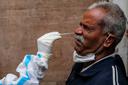 A health worker collects a nasal swab sample from a Border security force (BSF) at Madhyamgram Rural Hospital.
India reported 168,000 new Covid cases which included 4,461 cases of Omicron variant. Rapid testing and mass-vaccination has been ramped up. Govt of India begins a "precautionary" third booster dose for frontline, healthcare workers and 60-plus citizens with comorbidities.