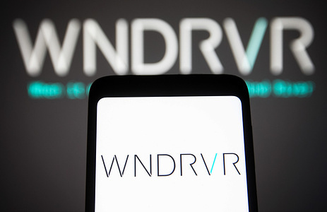 In this photo illustration, the Wind River Systems Inc. logo is seen on a smartphone screen and in the background.
