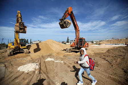 A Palestinian schoolboy walks past Egyptian excavators working at the construction of the city of "Misr 3" in the American School neighborhood in the city of Beit Lahia northern Gaza Strip.
The Egyptian Committee for the Reconstruction of the Gaza Strip had announced its donation of 500 million dollars in June 2021 as assistance from the Egyptian government for the reconstruction of the Gaza Strip after the fighting round between Hamas and Israel in May 2021.