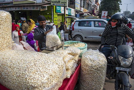 Shopkeeper weighing popcorn for customers on the eve of Lohri festival at Naya Ganj Market.
Lohri is a popular harvest festival, celebrated majorly in the North of India and primarily by Hindus and Sikhs from the Punjab region. Lohri marks the end of winter, and is a traditional welcome of longer days and sun's journey to the northern hemisphere in the Punjab region.