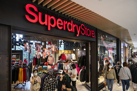Shoppers walk past the British clothing brand, Superdry store and logo in Hong Kong.