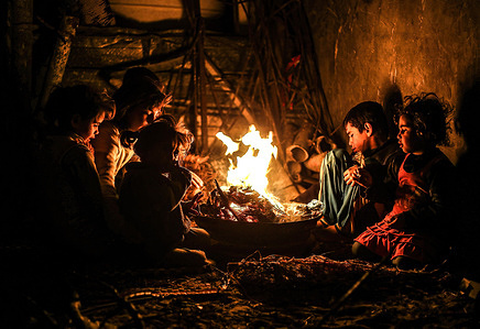 Palestinian children sit around a fire to keep themselves warm in front of their house during a rainy and windy day on the outskirts of Khan Yunis refugee camp in the southern Gaza Strip.