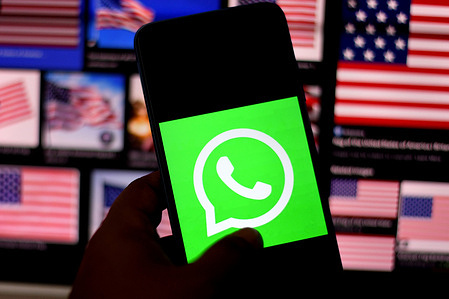 In this photo illustration, a WhatsApp logo seen displayed on a smartphone with Flags of the United States in the background.