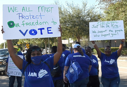 People march with placards in support of voting rights during a parade ahead of Martin Luther King, Jr. Day in Eatonville, Florida. Eatonville is the oldest black-incorporated municipality in the United States.