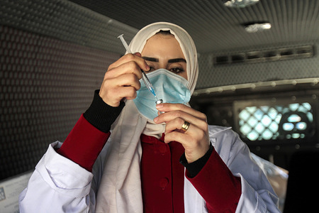 A Palestinian doctor prepares a dose of Covid-19 vaccine inside a Palestinian police car used as a mobile vaccination clinic in Derastia in the West Bank.