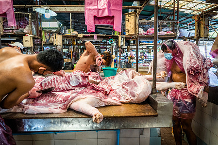 Workers butcher pig meat before it is sold in the market.
Workers at Bangkok Noi wholesale market prepare freshly slaughtered pig’s meat for sale. Due to a supply shortage, market speculation, and a potential outbreak of the African swine fever, the cost of pork in Thailand is skyrocketing, causing the price of the staple food to soar. The rapid inflation has resulted in a sudden country-wide increase in everything from street food to supermarkets.