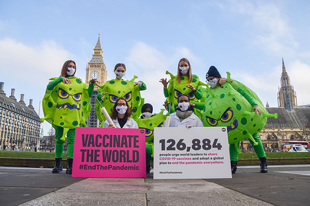 Activists wearing coronavirus costumes and doctor outfits stand next to placards calling on the UK government to share vaccines with other countries during the Vaccinate The World Campaign.
Activists from ONE UK, a global movement working to end extreme poverty and preventable diseases by 2030, staged a campaign wearing coronavirus and doctor costumes in Parliament Square, calling on the UK government and world leaders to share vaccines with low-income countries, vaccinate the world and end the COVID-19 pandemic.