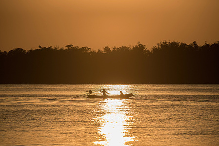 Local fishermen are seen sailing on their boat during the sunset at the Chao Phraya river.