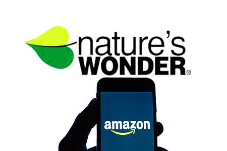 In this photo illustration an Amazon logo seen displayed on a smartphone with a Nature’s Wonder logo displayed in the background.