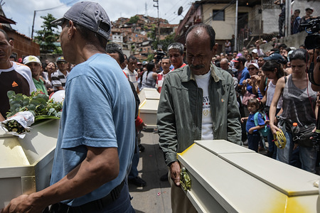 Relatives seen carrying the coffins of the victims during the funeral. 
The victims, Roxana Conde (10 years old), Julianyerli Conde (4 years old), Jonás Jonneiker Conde (1 year old) and Humberto Ruiz (10 years old), were murdered last September 14th in El 70 in Caracas, Venezuela. The perpetrator was identified as José Manuel Morgado (48 years old) who was killed the same night after a shootout with police officers (CICPC) while fleeing in Ocumare del Tuy, Miranda state, Venezuela. The suspect raped the children before killing them using a hammer.